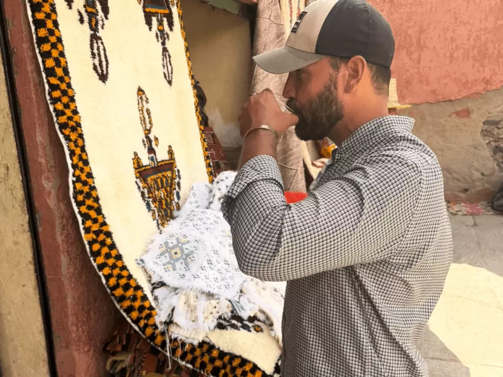 VOLZAR founder selecting handmade rugs at a market in Morocco — VOLZAR