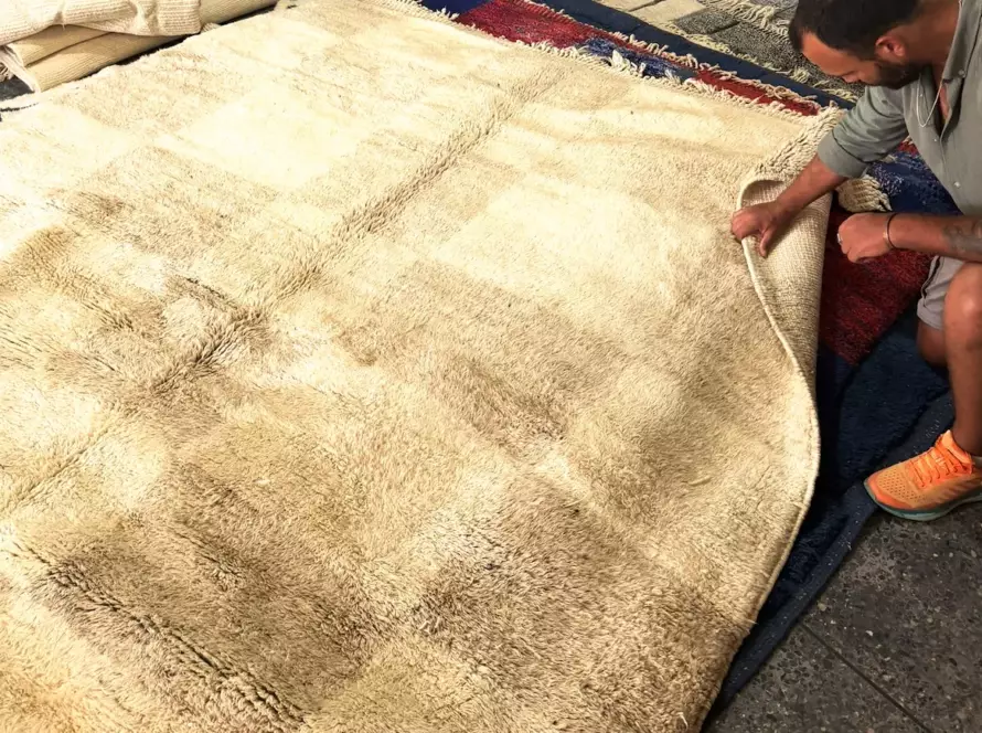 Christophe examining wool rug texture by hand, Morocco — Volzar selection process